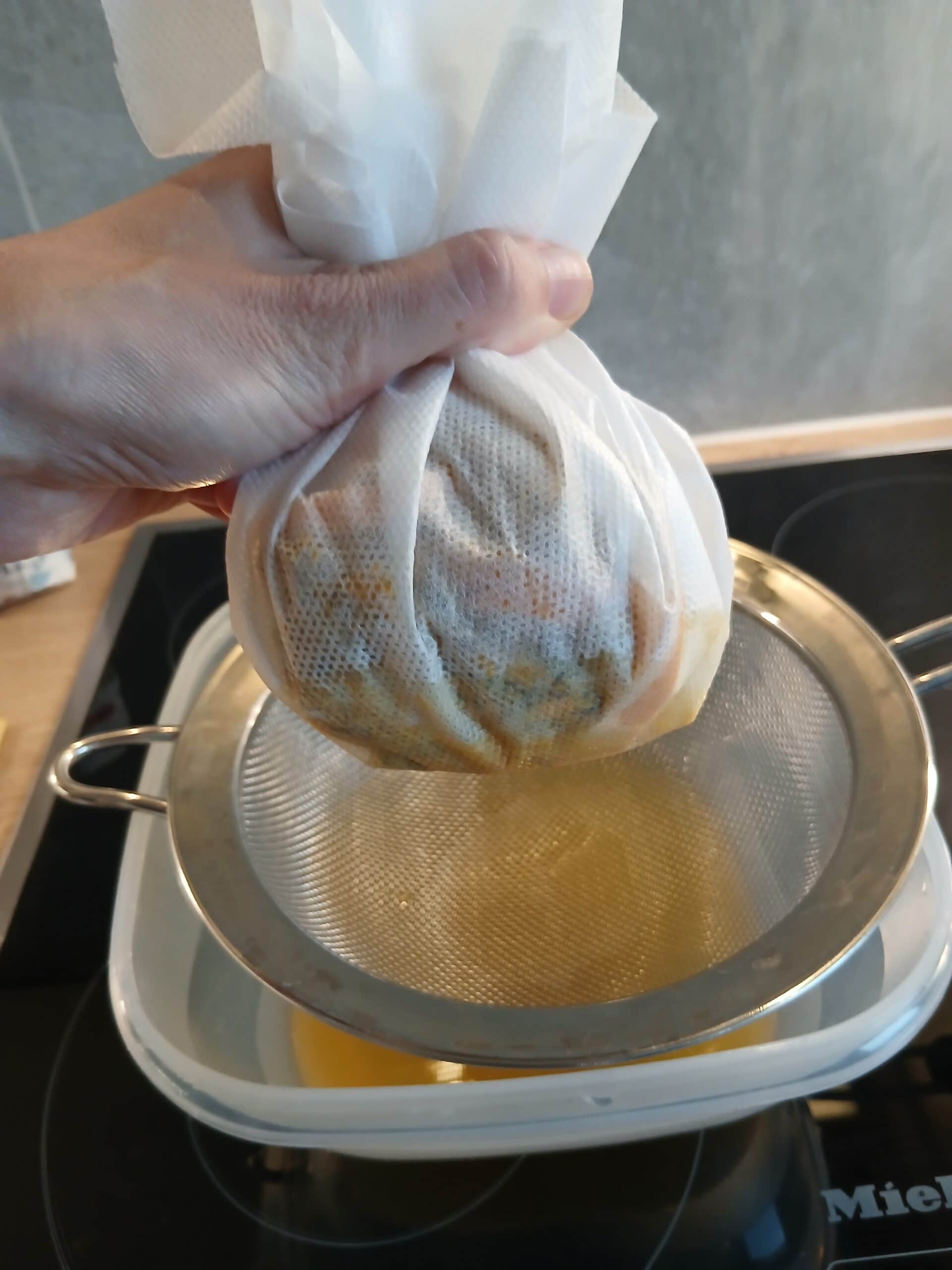 Das Abseihen des Löwenzahnhonigs durch ein Seihtuch