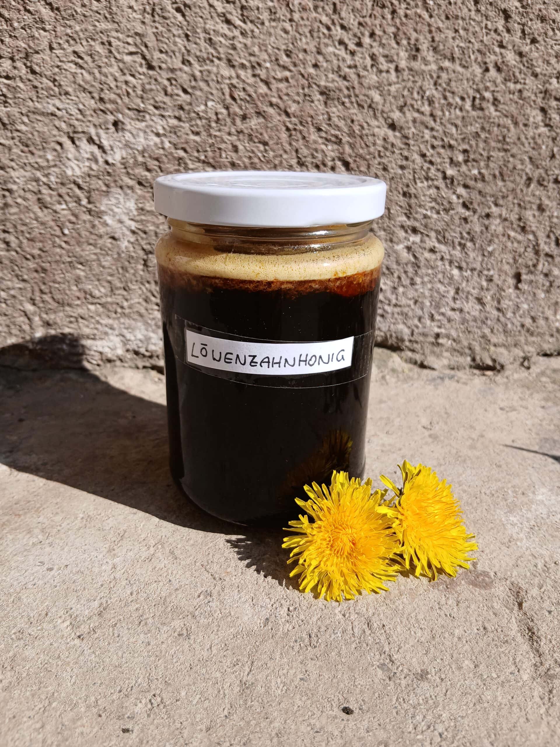 Ein Glas Löwenzahnhonig und Löwenzahnblüten