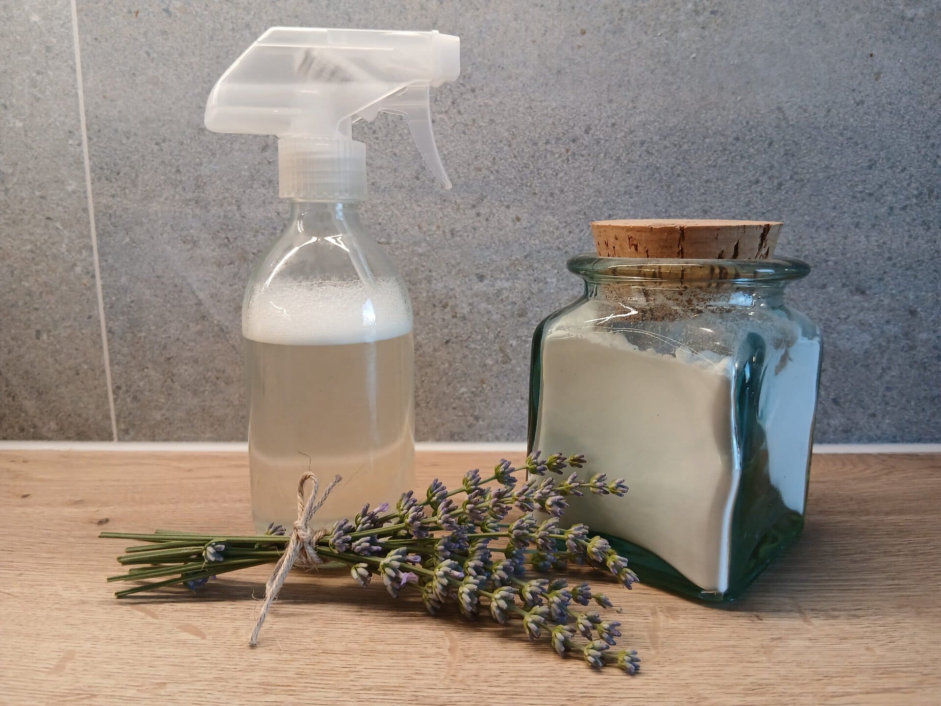 Eine Sprühflasche mit Allzweckreiniger mit einem Glas Waschsoda und einem Lavendelstrauß